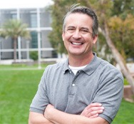 man smiling outside with arms crossed