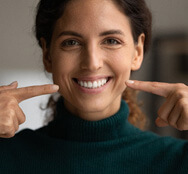 smiling woman pointing at her smile