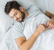 a man resting on his bed with his head elevated