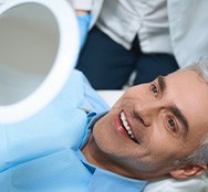 a patient checking his smile with a mirror