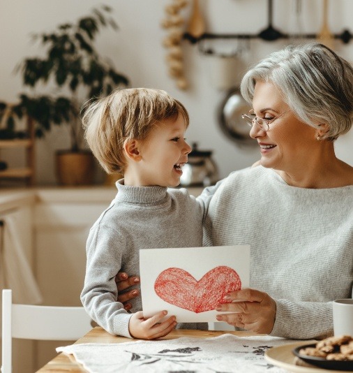 Older woman smiling at child after dental implant tooth replacement