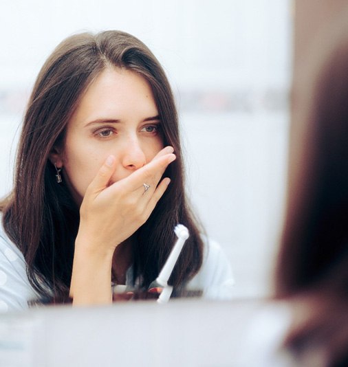 Concerned woman covering her mouth and holding toothbrush