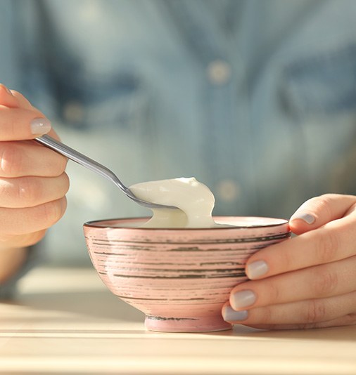 Woman eating a bowl of yogurt, a soft food