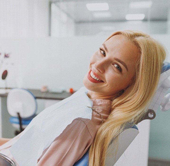 Blonde woman leaning back in dental chair and smiling
