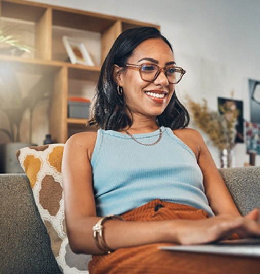 Woman with glasses working on laptop and smiling