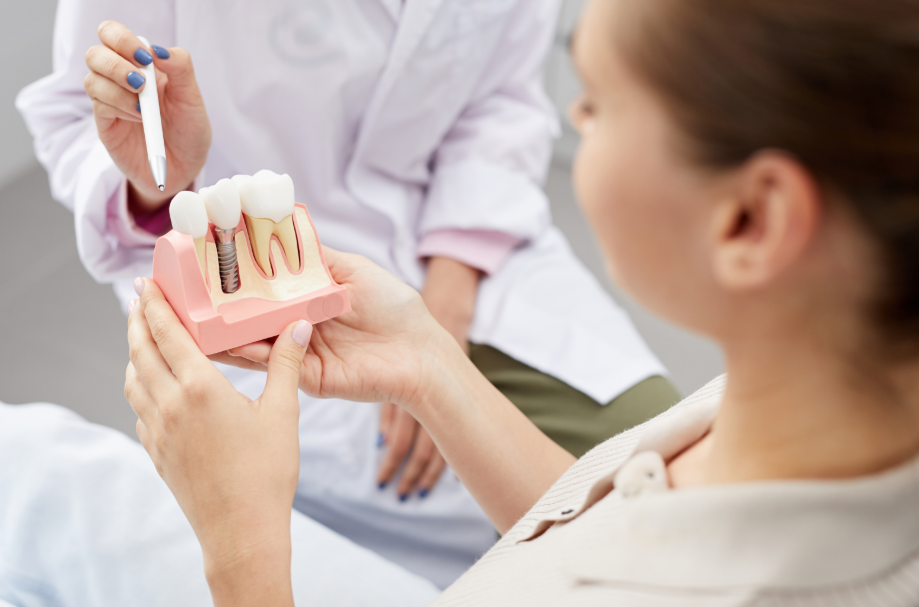Dentist showing patient enlarged dental implant model